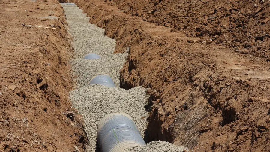 Open trench in a yard exposing a residential sewer line during a repair
